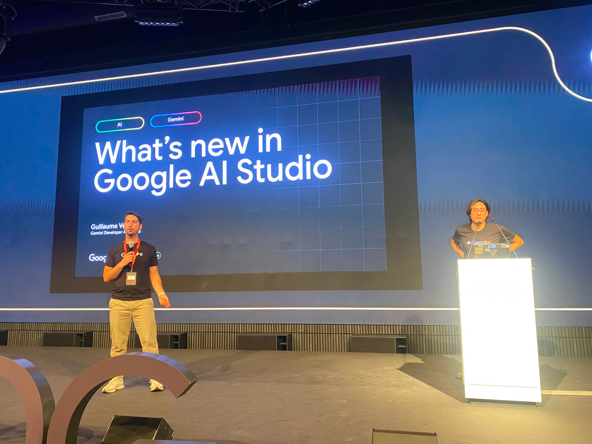Alessandro Palmieri and Guillaume Vernade stand on a stage in front of a large presentation slide that reads 'What's new in Google AI Studio'.